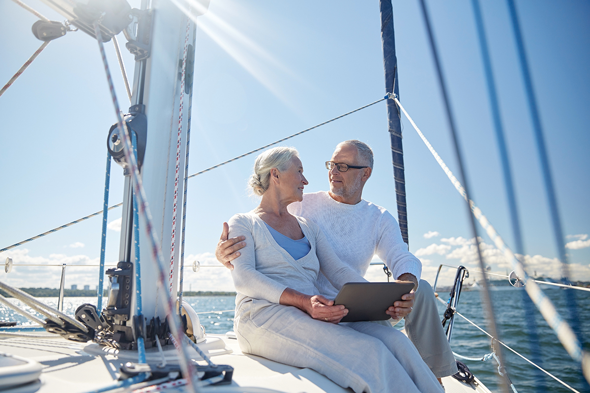 senior couple with tablet pc on sail boat or yacht